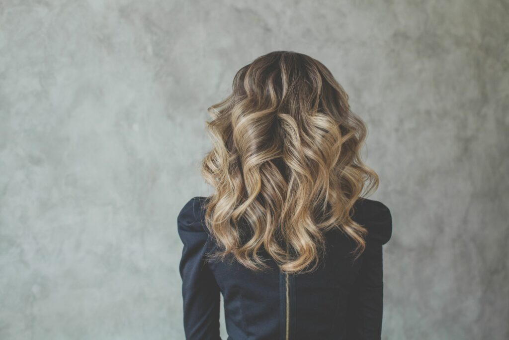 woman in black shirt facing away with brown hair styled using a balayage technique